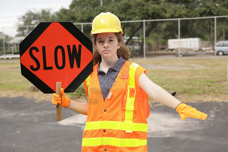 一名女建筑工人用道路标志和手势减缓交通速度图片
