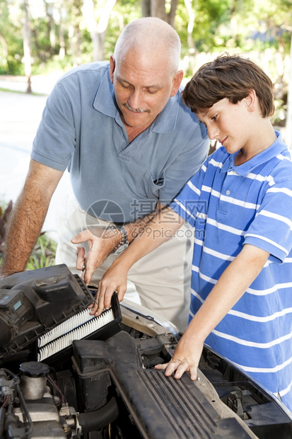 男孩帮助父亲换车引擎的空气过滤器图片