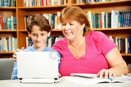 母亲或教师用图书馆的电脑上学习图片
