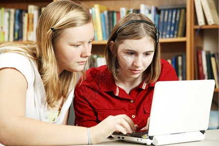 两名认真的学生使用计算机在学校图书馆做功课图片