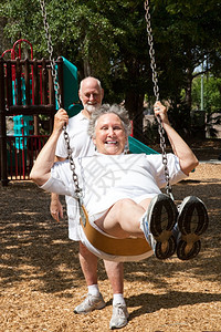 年长的女人在公园操场上摇摆她丈夫在推图片