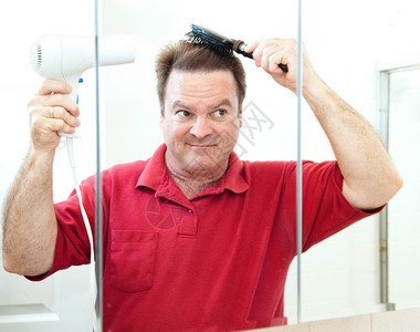 成年男子在浴室镜里吹干头发图片