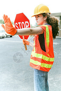 年轻女建筑学徒持有停车牌并指挥交通图片