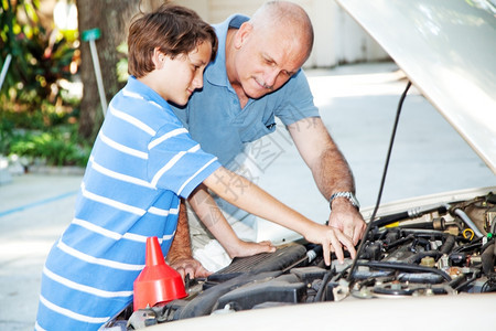 父亲教他儿子如何检查家庭车的引擎图片