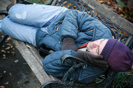 无家可归的人睡在公园长椅上图片