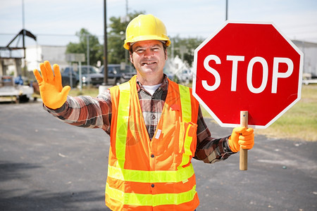 路边友善的建筑工人举起一个停车牌图片