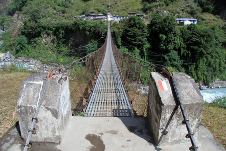 尼泊尔的暂停使用桥和靠近河流的村庄图片