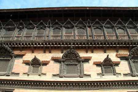 尼泊尔Bhaktapur宫的木制窗户遮盖砖墙图片
