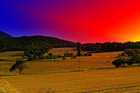 法国阿尔卑斯山的田园环绕着Fields环绕的农场日落图片