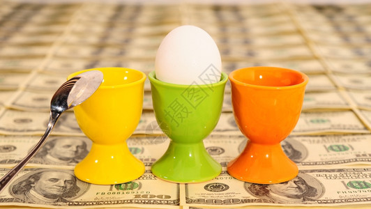三个鸡蛋在背景的里有很多美国百元钞票图片