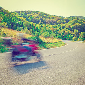 在意大利阿尔卑斯山的刮风失速路上运动模糊的摩托车手Instagrameffect图片