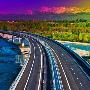 位于皮埃蒙特的现代高速公路位于雪峰阿尔卑斯山的背景日落图片