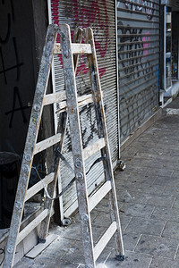 在特拉维夫修理商店的假木制梯子在街上喷洒了铁板图片