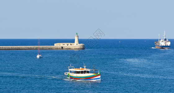 货船离开瓦莱塔港灯塔是马耳他港口的入口海湾盆地的游艇图片