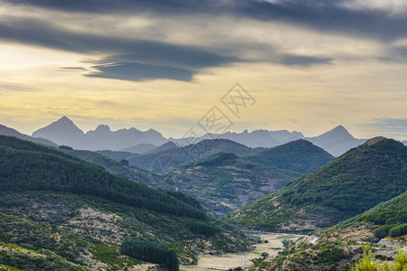 在西班牙美丽的景色中坎塔布里亚山脉的景色日出时沿干河床运行的电线图片
