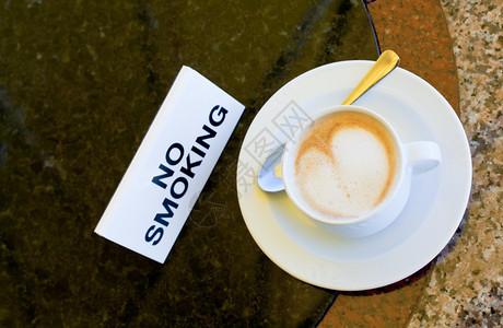室外咖啡厅不吸烟桌上的卡布奇诺咖啡杯图片