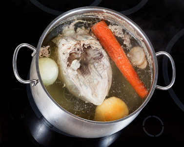 在玻璃陶瓷锅炉上用钢里煮鸡汤和调味蔬菜图片