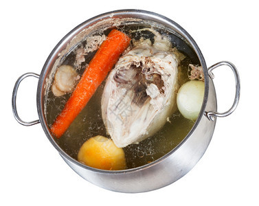 在白底绝缘的钢锅里煮鸡汤和调味蔬菜图片
