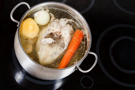 煮鸡汤在玻璃陶瓷锅炉上用钢里调制蔬菜图片