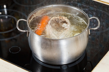 用玻璃陶瓷锅炉在钢中调制蔬菜煮鸡汤图片