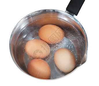 以白色背景隔离的电炉灶金属锅中沸煮鸡蛋的顶部视图图片