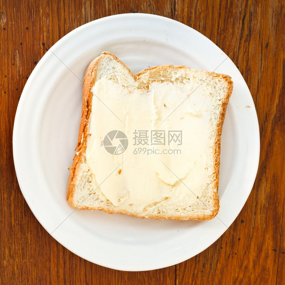 木制桌上白板面包和黄油三明治的顶部视图图片