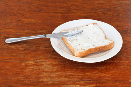 烤面包和干酪三明治白盘上加草药木桌用餐刀图片