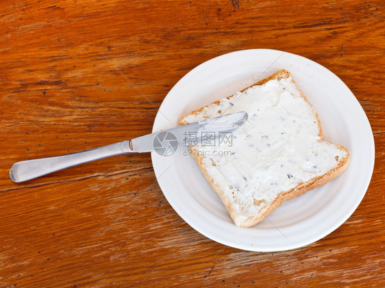 从吐司和土上方的三明治和白板上含有草药的土豆和三明治木桌上的餐刀图片