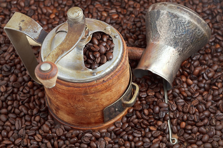 在许多烤咖啡豆上人们可以看到古老的手工咖啡加厂和铜锅背景图片