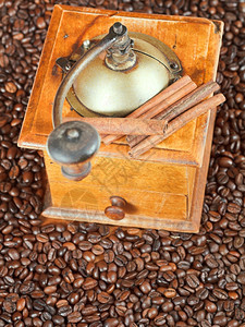 在许多烤咖啡豆和肉桂树上看到倒影手制咖啡研磨机的顶部图片