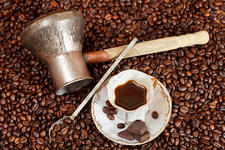 最顶端一小杯咖啡和加巧克力棒咖啡壶的烤豆图片