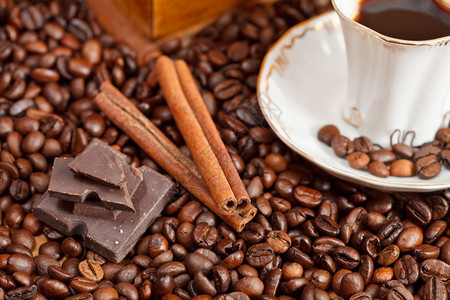 小杯咖啡和烤豆配有古老木制手工磨坊肉桂巧克力条图片