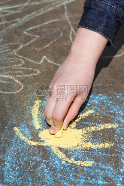 女孩在蓝天空中涂黄太阳在户外沥青上涂彩粉笔图片