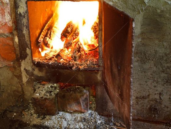 在开着的门熔炉中燃火烧灼的木柴图片