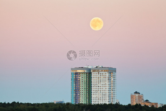 夏夜在城市住宅上空粉红天中满月图片