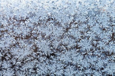 寒冷的冬夜晚冻结窗口上的雪花和冻状图片