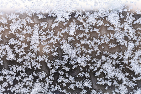 寒冷的冬夜晚窗帘上的雪花和霜冻模式图片