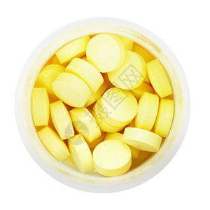白色背景隔离的圆塑料瓶中黄药片的顶部视图图片