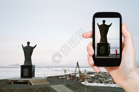 旅行概念在俄罗斯阿纳迪尔Chukotka的AnyrskyLiman上用移动工具拍摄圣尼古拉纪念碑照片的游客图片
