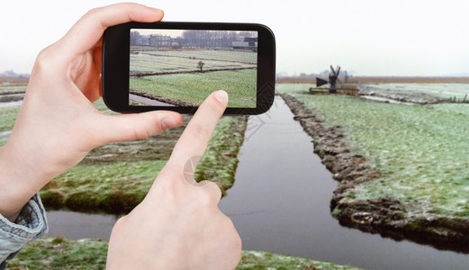 旅行概念旅游者用移动工具拍摄冬季荷兰冷冻运河的照片图片
