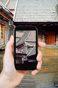 旅行概念在挪威卑根尔的雨中木屋照相的旅游者图片
