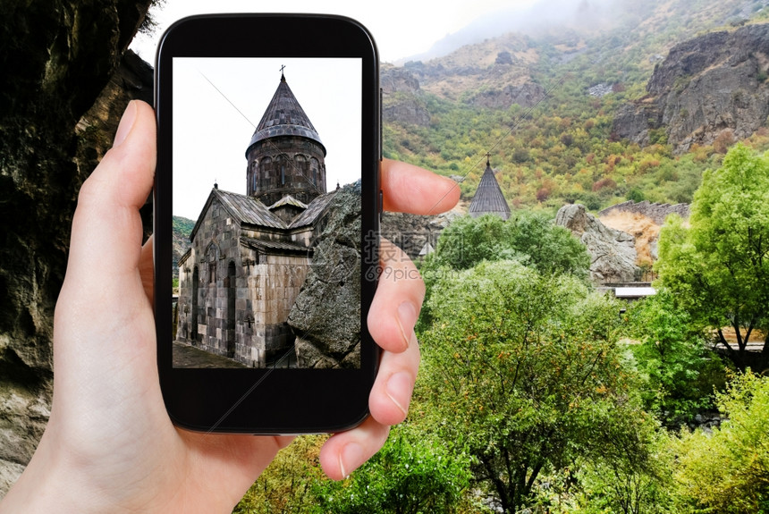 旅行概念游客用智能手机拍摄亚美尼中世纪盖格哈德修道院的Katoghiken教堂图片