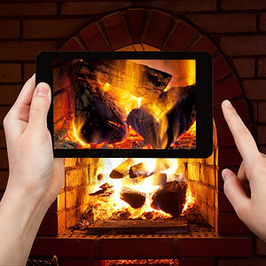 旅行概念游客在晚上用智能手机拍摄壁炉烧木柴的照片图片