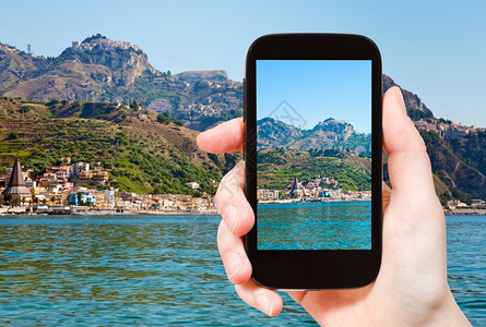 旅游概念旅游者拍摄Taormina山区和西里智能手机上的GardiniNaxos海滩的流行旅游度假胜地Taormina图片