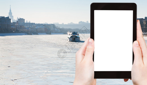旅行概念在阳光明媚的冬季日莫斯科河冰冻的上在平板电脑上拍摄旅游影冰船照片在屏幕上剪出空白的广告标志位置图片