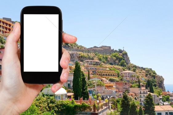 旅行概念意大利西里Castelmola镇Taormina度假胜地城市的旅游照片在平板电脑上拍摄有空白广告标志的屏图片