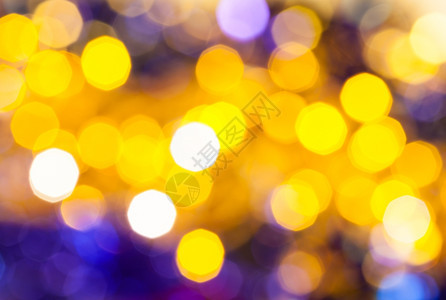 抽象的模糊背景暗黄色和紫闪烁着Xmas树上电动园地的圣诞灯光图片