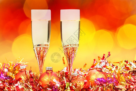 圣诞节死寂生命金色X马装饰品两杯闪亮葡萄酒红色和黄模糊的圣诞灯背景图片
