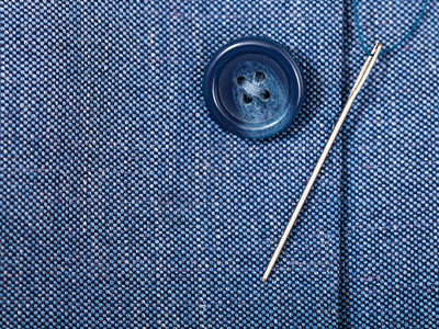用紧合的针把扣子与蓝色丝绸组织捆绑在一起背景图片