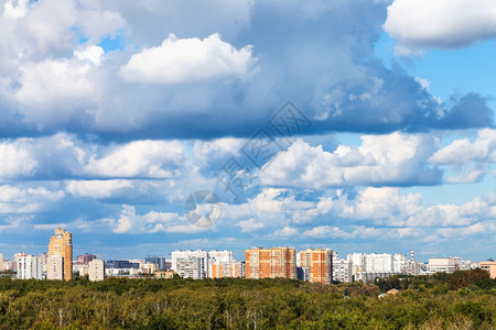 夏季绿色森林和城市上空的低蓝云图片